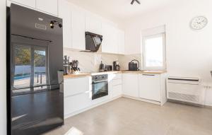 a kitchen with white cabinets and a black refrigerator at Holiday home Iva by Villas Guide in Vrulje