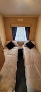 two beds in a small room with a window at Stunning Holiday Home Beautiful Lakeside Views 15 Mins from Goodwood in Merston