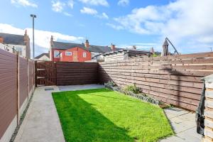 a backyard with a retaining wall and green grass at Brough Street 4 Bed, 5 Guests in Goole