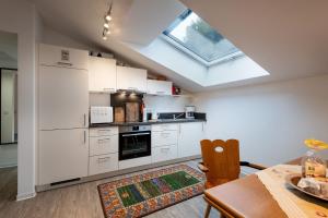 オーバーアウドルフにあるFerienwohnung am Luegsteinseeの白いキャビネットとテーブルと窓のあるキッチン