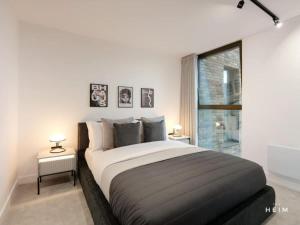 una camera bianca con un grande letto con due tavoli di Solaro at The Heim Residences a Manchester