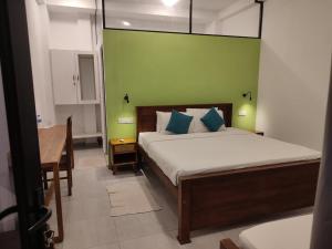 a bedroom with a bed and a desk and a green wall at Weligama Ocean Breeze in Weligama