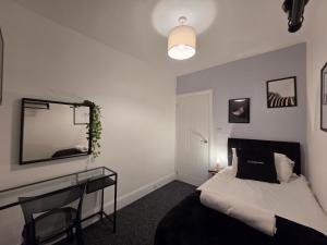 ein Schlafzimmer mit einem Bett, einem Schreibtisch und einem Spiegel in der Unterkunft Modern 5 Bedroom Retreat, With Valley Views, Near Bike Park Wales in Troed-y-rhiw