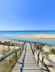 einen Holzweg zum Strand mit dem Ozean im Hintergrund in der Unterkunft La casa di Caterina in Avetrana