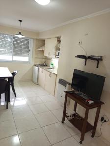 a living room and kitchen with a table and a television at Azul y Verde in Necochea