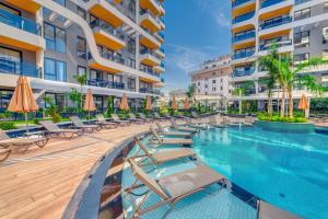 an outdoor swimming pool with lounge chairs and umbrellas at 'Ultra Luxury Holiday Apt in the Heart of the City in Alanya