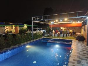 a swimming pool at night with a group of people sitting at อู่ตะเภาโฮมสเตย์byต้นไทร in Ban Nong Sa