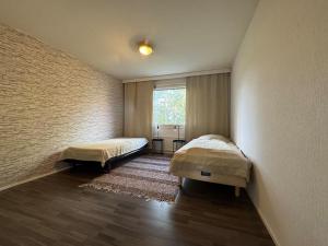 een slaapkamer met twee bedden en een raam bij Kotimaailma - A cozy apartment for business guests in Seinäjoki