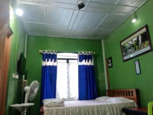 a bedroom with a bed and a window with blue curtains at deiphi and risa homestay in Pynursla