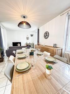 a table with plates and glasses on it in a living room at Le Grand Horizon Rochelais, plage à 5min, parking in La Rochelle