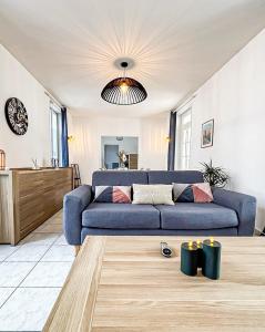 a living room with a blue couch and a table at Le Grand Horizon Rochelais, plage à 5min, parking in La Rochelle