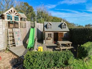 a backyard with a play house and a wooden fence at Swallows Cottage in Walton East