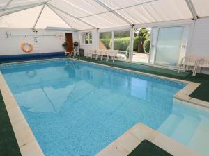 a large swimming pool with a tent and a swimming pool at Swallows Cottage in Walton East