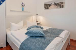 ein weißes Bett mit blauen Kissen darüber in der Unterkunft Paul-Kühne-Str 4 Tintenfisch in Ostseebad Koserow