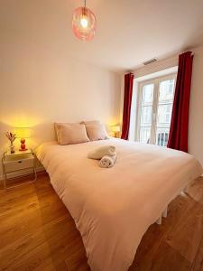 Un dormitorio con una gran cama blanca con cortinas rojas. en Joli Perot, en La Rochelle