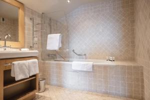 a bathroom with a tub and a sink at Les Trois Vallées, a Beaumier hotel in Courchevel +43 photos