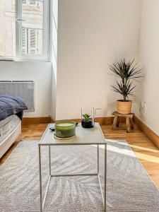 a coffee table in a living room with a plant at Les Saints Nico à 5 min Port, Gare & Centre in La Rochelle