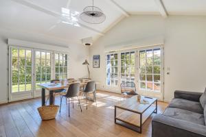 ユリューニュにあるVillas Odalys Le Domaine de Lanaのテーブルと椅子とソファのあるリビングルーム