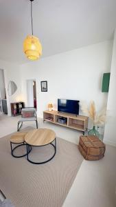 a living room with two tables and a television at Maison Du Marché in La Rochelle