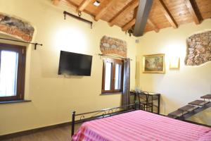 カパンノリにあるVILLA GIOVANNA - Guest House Luccaのベッドと壁にテレビが掛かった寝室