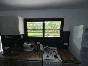 een keuken met een fornuis, een wastafel en een raam bij El EDEN in Mar de Cobo