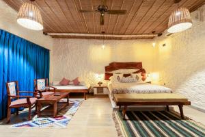 a bedroom with a bed and a table and chairs at Dunes & You - A Desert Retreat in Govindgarh
