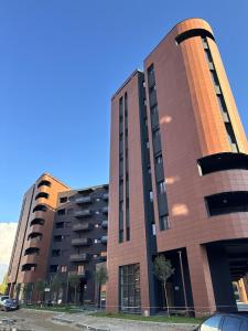 地拉那Luxury Flat In Tirana的一座大型砖砌建筑,前面有汽车停放