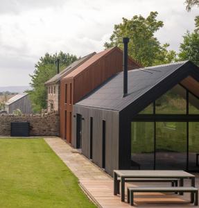 una casa con techo negro y dos bancos en Limeworks Hemmel, en Holburn