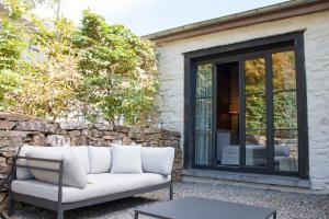 a white couch sitting on a patio next to a stone wall at La Chambre de la Gotale in Manhay