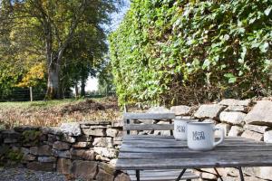 twee koffiekopjes op een houten bankje bij La Chambre de la Gotale in Manhay