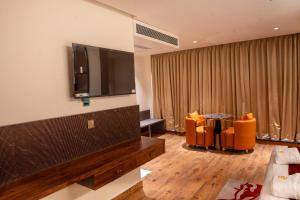 - un salon avec une télévision à écran plat et des chaises orange dans l'établissement Hotel Golden Amulya Rest Wings, à Yelahanka