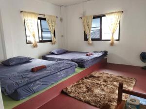 two beds in a room with two windows at Phumokdokmai Resort in Ban Seng Choi
