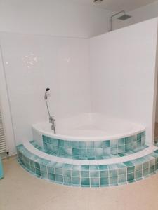 - une baignoire dans une chambre blanche revêtue de carrelage bleu dans l'établissement Un Noël paisible, entre douceur,magie et surprise !, à Castelnau-de-Montratier