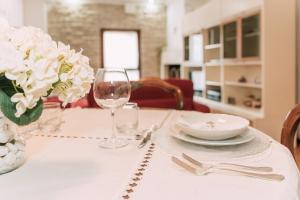 a table with a white table cloth with a plate and glasses at Palladio Apartment - Vista Fiume, In Centro con Garage in Vicenza +16 photos
