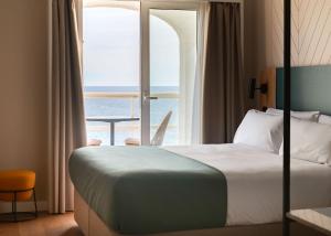 a hotel room with a bed and a large window at Limehome Benidorm Calle Mayor in Benidorm +42 photos