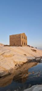 an old building on a hill next to a body of water at Dimora Garibaldi Apartment & Room in Agrigento +10 photos