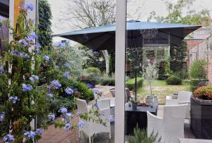 a patio with white chairs and an umbrella and flowers at Casa della Nonna in Diest +18 photos