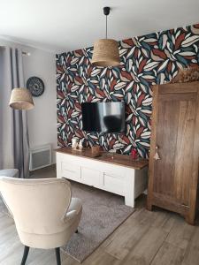 sala de estar con TV y silla en Le Gîte de Marguerite, en Néant-sur-Yvel