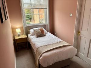 a small bedroom with a bed and a window at Aspen-free parking-Grade II listed-second floor two bedrooms apartment in Huntingdon