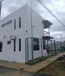 un bâtiment blanc avec une clôture verte devant dans l'établissement Coral House Fortuna, à Tanque