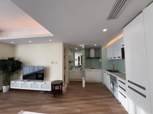 北京市にあるBeijing Yasmine Serviced Apartmentsの白いキャビネット、テーブル、テレビ付きのキッチン