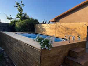 a swimming pool with a wooden deck next to a building at Casetta sull’Etna in Nicolosi