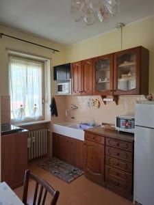 a kitchen with wooden cabinets and a sink and a refrigerator at Casa Camelia in Torre Pellice +16 photos