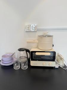 a toaster oven sitting on a counter with plates and glasses at The Calm Corner Summermall in Kota Samarahan +4 photos