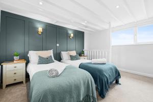 zwei Betten in einem Zimmer mit blauen Wänden in der Unterkunft 3-BR Luxe Cowes Cottage Harbour Views, Sleeps 6, with Private Garden - LONG TERM STAY SPECIAL OFFER AVAILABLE! - by Blue Puffin Stays in Isle of Wight