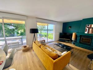- un salon avec un canapé jaune et une cheminée dans l'établissement Maison sur le golfe du Morbihan vue mer, à Plougoumelen