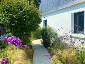 un jardin avec des fleurs violettes à côté d'un bâtiment dans l'établissement Maison sur le golfe du Morbihan vue mer, à Plougoumelen