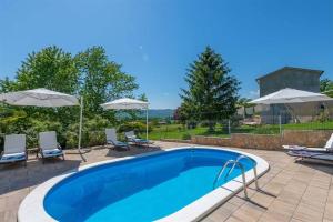 a swimming pool with chairs and umbrellas at Villa Emma in Lanišće