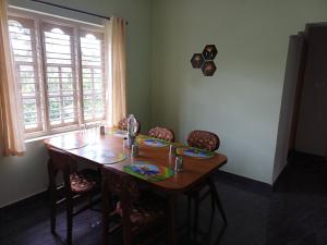 une table de salle à manger avec des chaises et une grande fenêtre dans l'établissement Èclairs Homestay, à Madikeri 5 autres photos