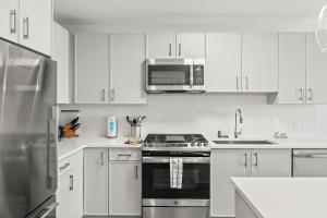 a white kitchen with a stove and a microwave at Luxury Modern Apartment Near Stamford Station in Stamford